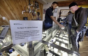 Cannabis City clerk Will Bibbs, left, helps a customer looking over a display case of marijuana products at the shop in Seattle in December. (Elaine Thompson/AP)