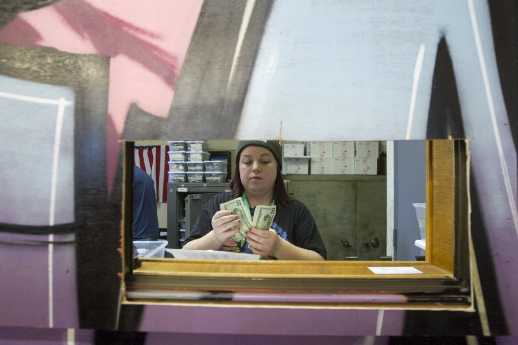 Janie Rayburn counts money as she works the till at Main Street Marijuana in Vancouver Friday December 26, 2014. The shop has seen a lot of changes in its first year in business. (Natalie Behring/ The Columbian) 