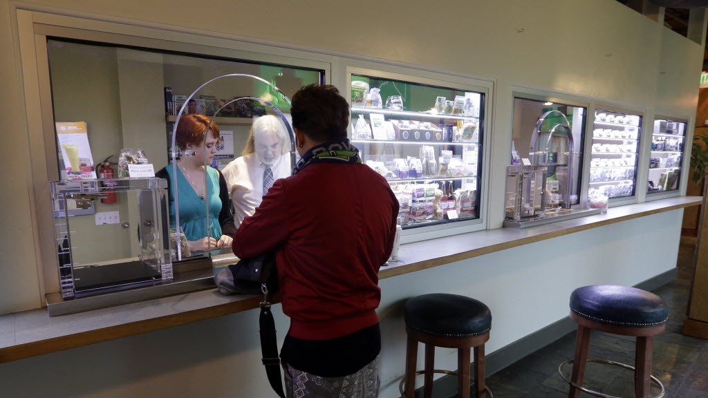 Store manager Bess Matthews, left, and co-owner Jake Dimmock assist a customer at a medical marijuana dispensary, Tuesday, Jan. 6, 2015, in Seattle.